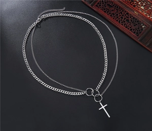 Detail of silver layered cross necklace with Cuban chain and punk style rings