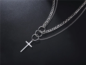 Detail of silver layered necklace with double chains, interlocking rings and cross pendant