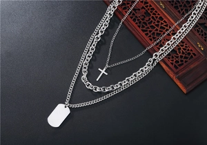Détail macro du collier multicouche en acier titane argenté avec croix et plaque militaire