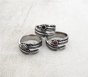 Detailed view of vintage silver feather rings with colorful stones on stone background