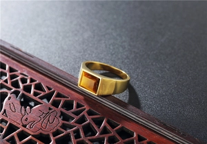 Detailed close-up of a gold-plated titanium ring featuring a rectangular tiger eye gemstone