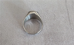 Detailed view of a silver punk cross ring in polished stainless steel on a textured fabric