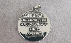 Detalle macro del colgante de San Miguel en plata con grabado religioso y enganche