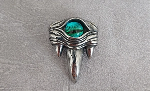 Detailed close-up of retro punk style evil eye ring with green gem and beast fangs