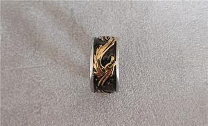 Gros plan détaillé d'un motif de dragon vintage gravé sur une large bague en acier titane