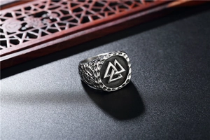Macro detail of Viking Valknut signet ring in vintage stainless steel on dark wood background