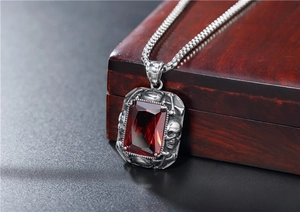 Détail macro du pendentif crâne gothique avec une grande pierre rouge sur sa chaîne