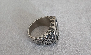 Macro detail of Viking stainless steel ring featuring hammered finish and Vegvisir compass