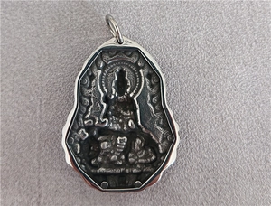 Macro detail of vintage silver stainless steel religious Buddha pendant with embossed carving