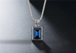 Dettaglio del ciondolo vintage con gemma blu rettangolare e trame sbalzate in argento