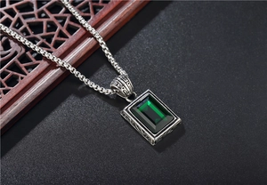Dettaglio macro del ciondolo smeraldo vintage con catena box argento e incisioni fini