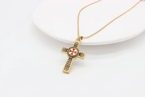 Detailaufnahme des goldenen Templer-Anhängers mit rotem Kreuz und keltischen Knoten