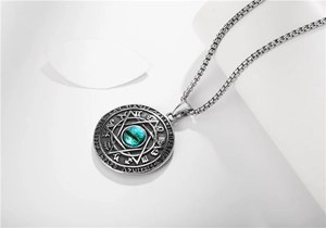 Macro view of stainless steel pendant featuring green cat eye stone and star engraving