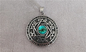 Macro shot of silver zodiac pendant featuring an emerald eye gemstone and star pattern