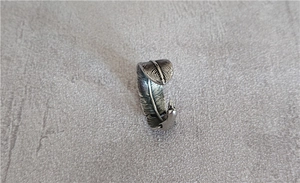Macro shot of vintage silver feather ring with detailed oxidized texture on gray surface