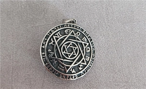 Detailed view of stainless steel medallion featuring hexagram and zodiac engravings