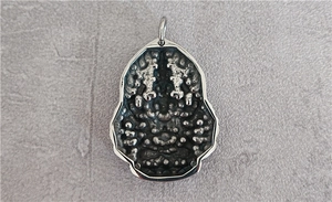 Macro detail of vintage steel Avalokitesvara relief pendant with industrial texture
