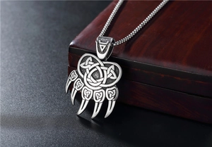 Close-up of Viking bear paw pendant with Celtic knot details on a wooden box