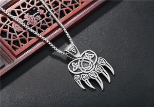 Close-up of Viking bear paw pendant with Celtic knot patterns on a steel chain