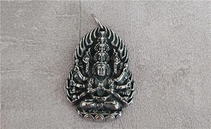 Detailed macro shot of vintage silver Avalokitesvara relief pendant with intricate deity carvings