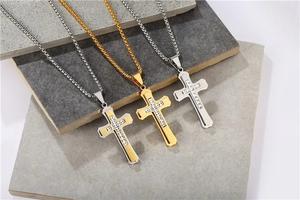 Détail de pendentifs croix double couche avec pierres serties sur chaînes box or et argent