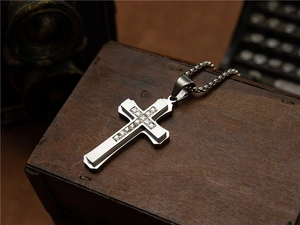 Détail d'un pendentif croix argenté avec cristal blanc sur une boîte en bois rétro