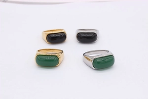 Detail view of retro saddle rings with emerald green and black onyx style gemstones