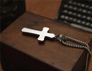 Détail du pendentif croix punk double couche sur une boîte en bois rétro texturée