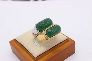 Macro view of gold and silver saddle rings with emerald green jadeite stones on a tray