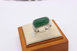 Macro shot of rectangular green jadeite stone set in a wide silver band ring