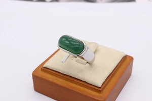 Detailed view of large oval green jade stone set in a wide silver band ring