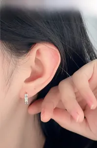 Vue macro d'une boucle d'oreille en argent 925 avec zircons scintillants sur un lobe d'oreille