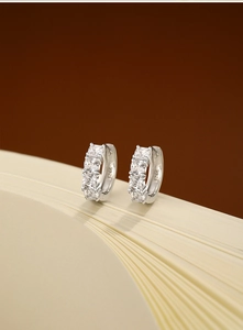 Gros plan de créoles en argent sterling S925 serties de zircons carrés sur des livres