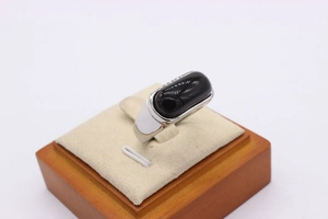 Macro view of men's silver ring with large oval black agate stone on a beige stand