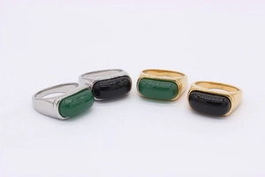 Macro detail of emerald green and black stone inlays on gold and silver rings