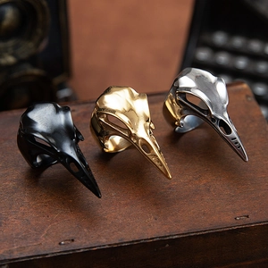 Gothic woodpecker skull rings in black, gold, and silver finishes on a vintage wooden box