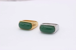 Detail view of gold and silver plated saddle rings with rectangular emerald green stones