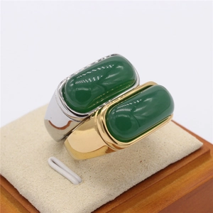 Men's gold and silver rings with large rectangular green emerald stones on display