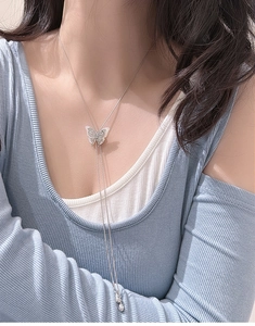 Detail of S925 silver butterfly tassel necklace with mother of pearl inlay on blue sweater