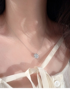 Gros plan d'un collier en moissanite avec grappe de fleurs porté par une femme
