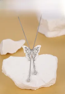 Detailed view of silver butterfly tassel necklace draped over a white textured stone