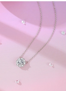 Vue détaillée du pendentif moissanite en grappe d'argent sur un fond rose clair élégant