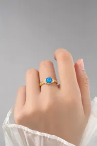 Detalle de un anillo vintage dorado con opale azul y circonitas en el dedo de una modelo
