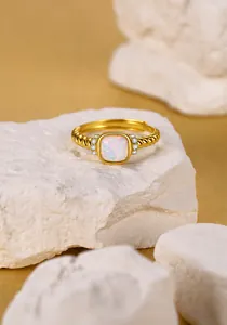Vista macro de anillo con opalo cuadrado y circonitas sobre banda trenzada retro