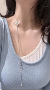 Detail of silver butterfly pendant with flowing tassel drops on a long elegant chain