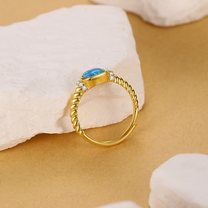Anillo ajustable vintage de oro con opalo azul y diseño de banda trenzada en piedra