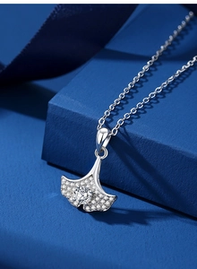Détail macro du pendentif feuille de ginkgo S925 avec moissanite sur soie bleue