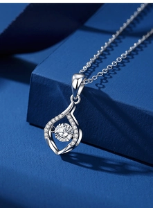 Macro shot of silver waterdrop pendant with dancing moissanite on blue texture