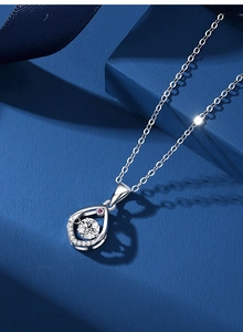 Macro view of teardrop pendant with dancing zircon and pink stone on silver chain