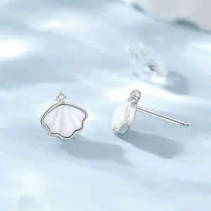 Detailed view of S925 silver shell earrings with zircon studs on a blue water wave surface